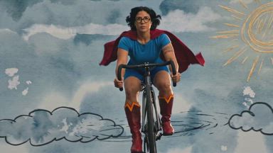 Supergirl gliding on her sports bicycle